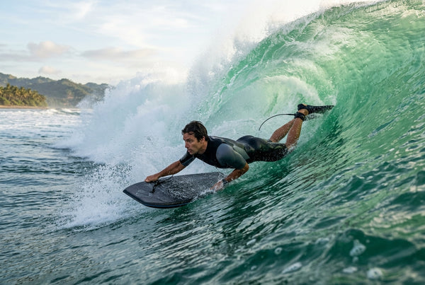 Bottom turn on a bodyboard, weight on the inside rail at the bottom of the wave