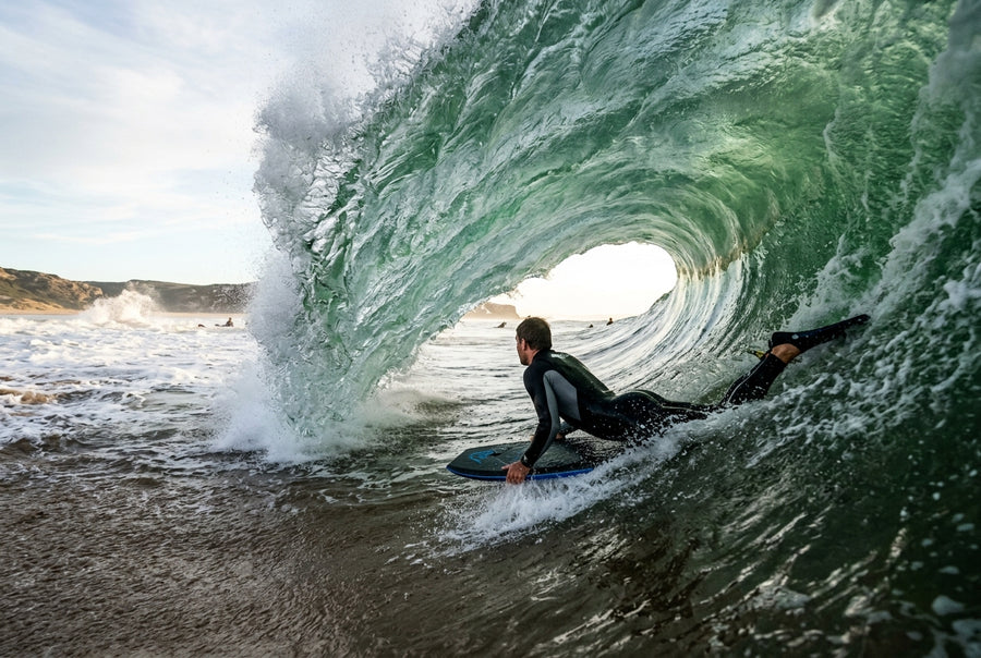 Bodyboarder in the tube of a hollow beach break wave