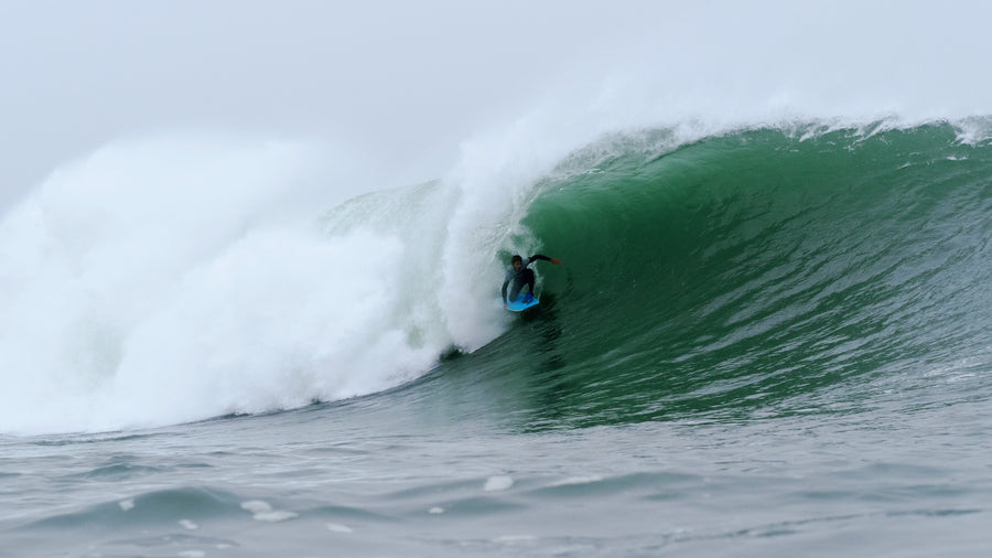 Bodyboarder en posición drop-knee, una rodilla sobre la tabla, en la pared de una ola