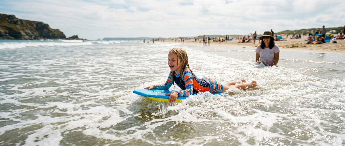 Smiling child on a small foam bodyboard in the whitewater at the water's edge