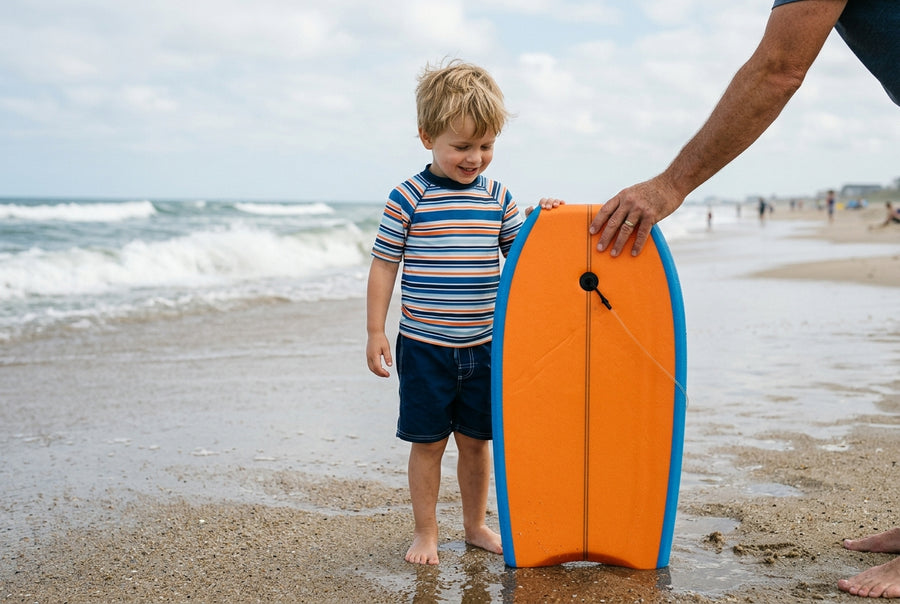 Child standing next to their bodyboard stood upright to check the size against the navel