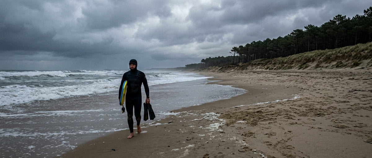 Sesión de bodyboard en invierno en una playa de las Landes, rider con traje de neopreno integral bajo un cielo gris