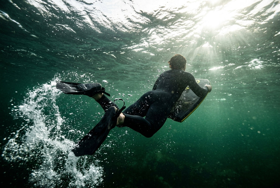 Bodyboarder pataleando bajo el agua para coger una ola